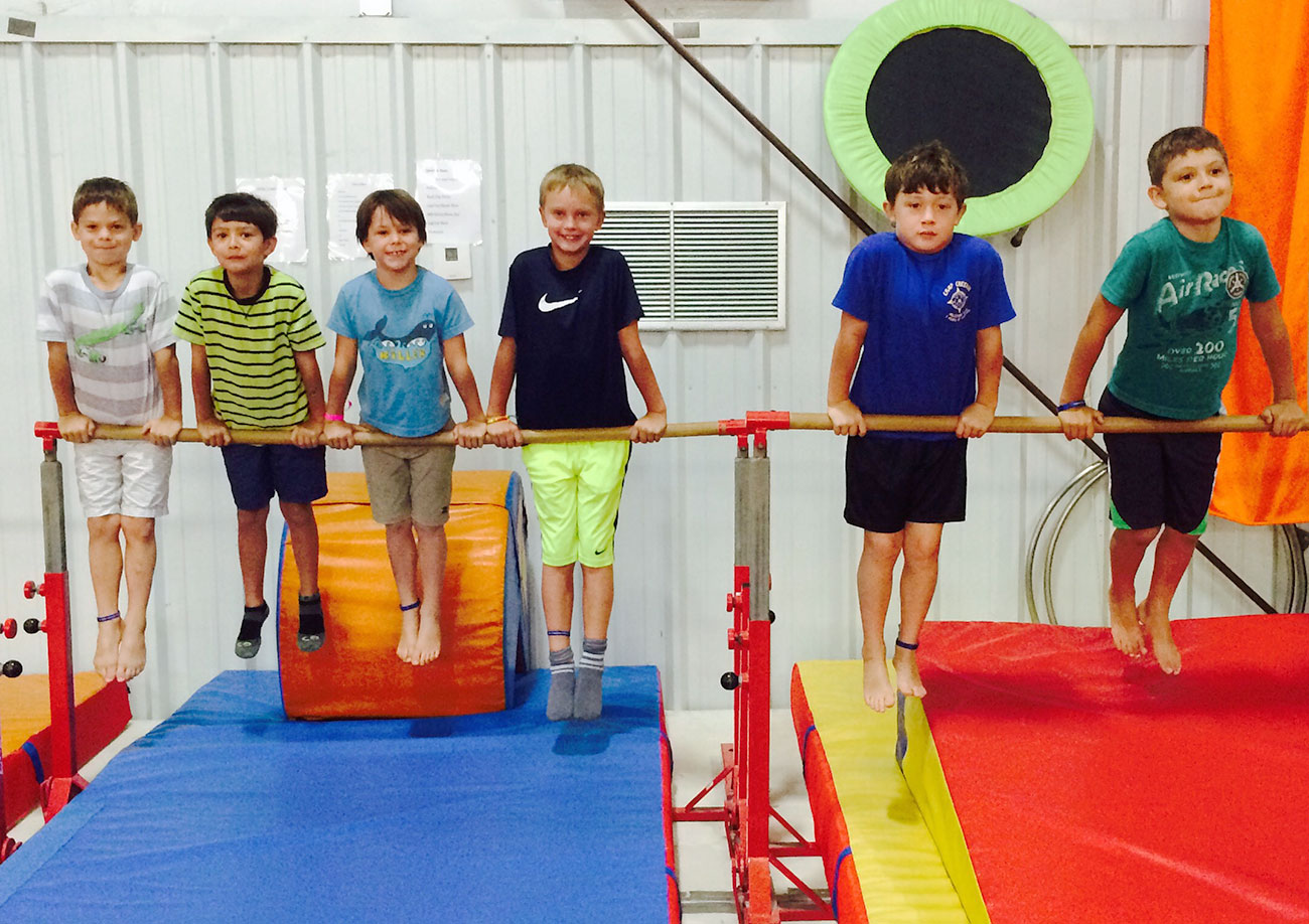 Several boys practice on a balance bar