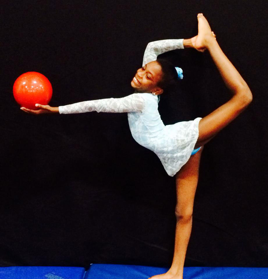 A girl practices ryhthmic gymnastics with a ball